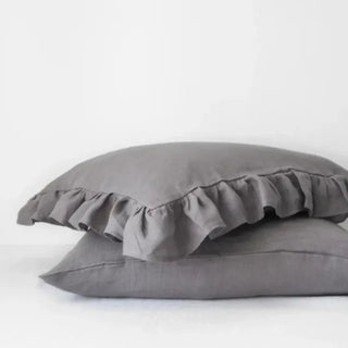 Ruffled linen standard pillowcase in dark grey, made from 100% flax linen, styled on a soft neutral bed – available in multiple colours and sizes from Arkaim Home.