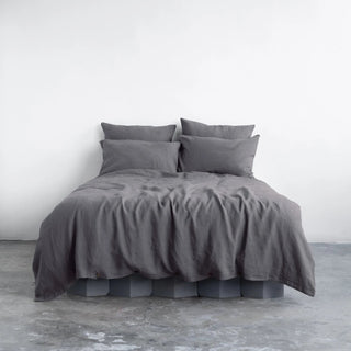 Dark grey linen pillows and duvet cover with coconut buttons, styled in a minimalist, scandi bedroom.