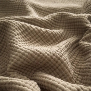 Nori cotton muslin throw in a warm neutral with soft fringed edges.