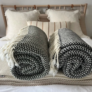 Close-up of black and white merino wool weave with hand-tied tassels, premium natural wool texture.