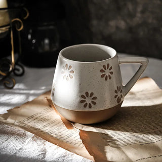 Nordic-inspired handmade clay mug with a white satin-speckled glaze and flower motif, perfect for tea or coffee.