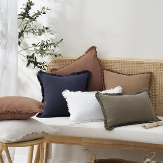 Fringed cotton cushion covers in white, ivory, olive green, terracotta and navy scattered on a rattan bench - natural, breathable, and perfect for layering in Scandi, Boho, minimalist or modern interiors.