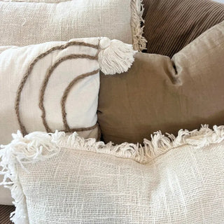 Textured white and brown cushions layered on a bed for a relaxed, coastal look.
