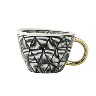 Handmade ceramic cup with black and white geometric design and a gold handle, minimalist and artistic in style.