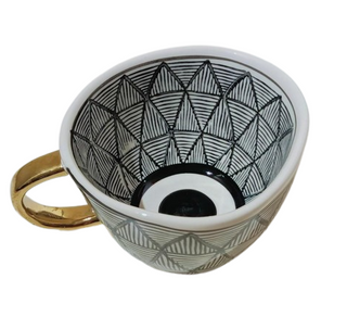 Handmade ceramic cup with black and white geometric design and a gold handle, minimalist and artistic in style.