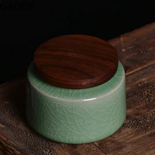 Elegant crackled glaze ceramic storage canister with a dark walnut lid, perfect for kitchen or home organization. Featuring a textured, artisanal design in a soft green hue, this airtight container is ideal for storing tea, coffee, spices, or small household items. A stylish and functional addition to natural homeware collections.