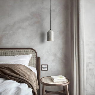 Grey terrazzo pendant lights hanging above a minimalist bedside table in calm, scandi interior.