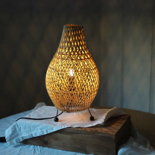 A woven rattan table lamp with a teardrop-shaped shade.
