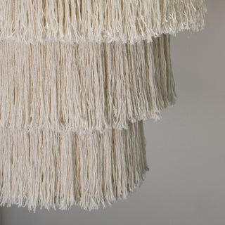 Close-up of a cream-coloured fringed lampshade with layered tassels.