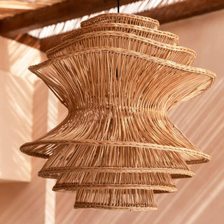 Natural handwoven dark rattan pendant light with organic, wave-like shape and soft ambient glow, ideal for boho and modern interiors.