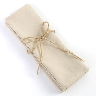 Set of four handmade ivory cotton table napkins with soft texture and minimalist design, styled for a modern table setting.