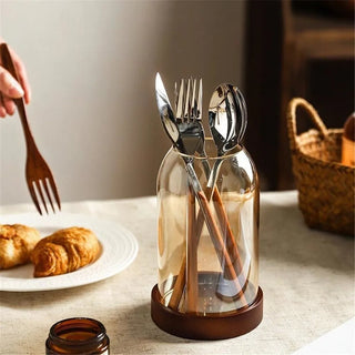Glass kitchen utensil jar with natural wood base and cutlery