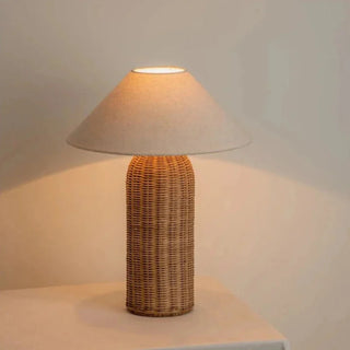 Woven wicker table lamp creating warm ambient light.
