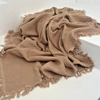 Latte brown cotton throw draped casually on white stairs.