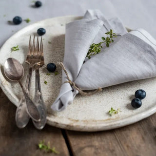 Set of two handmade light grey linen napkins with soft texture and natural drape, styled for an elegant, minimalist table.