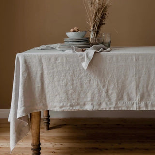 Light grey linen tablecloth on wooden dining table.