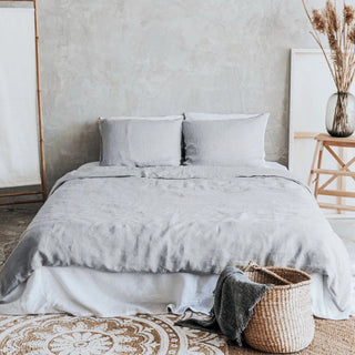 Light grey linen bedding set with zip closures, styled on a bed with two pillows and a cozy duvet, creating a calm, minimalist bedroom look.