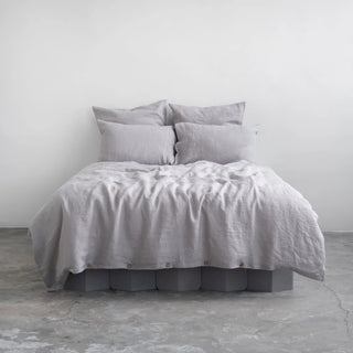 Light grey linen pillows and duvet cover with coconut buttons, styled in a minimalist, scandi bedroom.