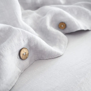 Close-up of light grey linen duvet fabric with coconut buttons.