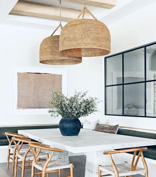 Large woven natural-fiber dome pendant lights hanging over a dining table.