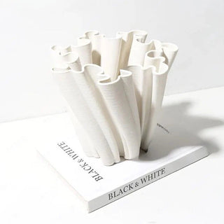 A sculptural, white decorative centerpiece bowl with an intricate, undulating design. The bowl's structure features twisted, fluted elements that create a dynamic, flowing appearance. The design is modern and minimalist, adding an artistic touch to home decor.