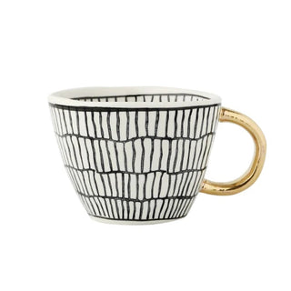 Handmade ceramic cup with black and white geometric design and a gold handle, minimalist and artistic in style.