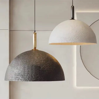 Black and white dome pendant lights with warm glow, minimalist design, suspended from ceiling.