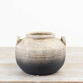 Handcrafted terracotta pot with rounded silhouette and handles.