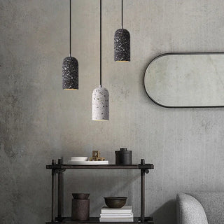 Set of black and grey terrazzo pendant lights hanging above a minimalist wooden console and mirror.