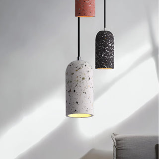 Set of black and grey terrazzo pendant lights hanging above a minimalist living room.