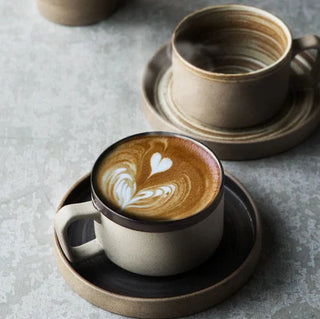 Miri stoneware mug and saucer set with spiral pattern in speckled oatmeal glaze, styled for modern and rustic tableware. Perfect for milk, tea, or coffee.