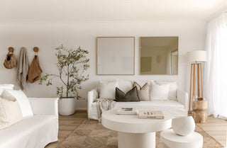 Coastal inspired modern living room with white furniture, decorative pillows, jute rug and natural accents.