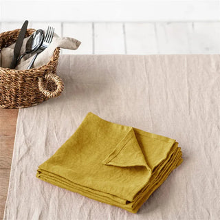 Yellow table napkins set on a dining table with rattan basket, minimalist cutlery and wood accents.
