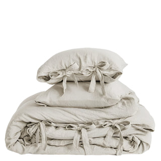 Beige linen bedding set with a duvet cover and two pillowcases tied with ribbon bows.  Perfect for a modern, Boho, Nordic or coastal bedroom styling.