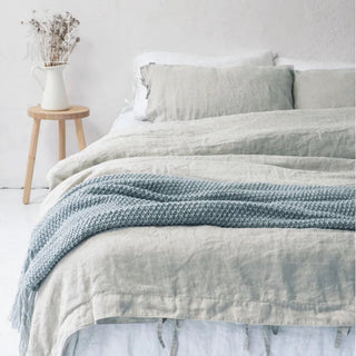 Natural linen bedding set with tie closures, styled on a bed with two pillows and a cozy duvet, creating a calm, minimalist bedroom look.