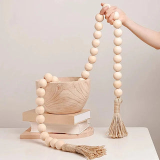 A nature-inspired oversized Wooden Bead Garland, handcrafted from natural wood and finished with bold hemp tassels. This rustic, boho décor piece adds relaxed charm to any interior, perfect for styling on trays, plant pots, candle holders, or hanging on walls and doors for a chic, earthy touch.