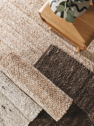Textured woven rugs in warm beige, cream, and dark brown tones.