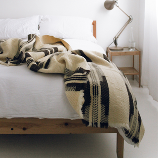 Shevitza virgin wool blanket in natural tones styled on bed – Arkaim Home
