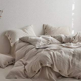 Beige bedding set with coconut buttons on a minimalist bed against a white wall.