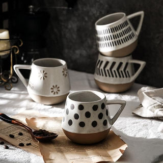 Nordic-inspired handmade clay mugs with a white satin-speckled glaze and black graphic motifs, perfect for tea and coffee.