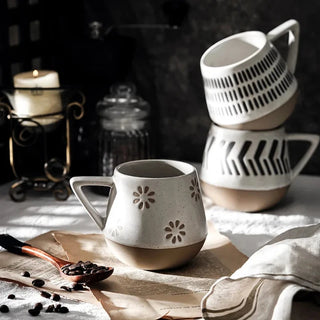 Nordic-inspired handmade clay mugs with a white satin-speckled glaze and black graphic motifs, perfect for tea and coffee.