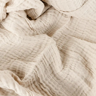 Beige cotton muslin throw with soft textured finish.