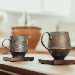 Handmade stoneware mug with a bronze metallic glaze, inspired by wabi-sabi aesthetics, displayed in soft natural light.