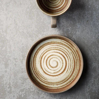 Miri stoneware mug and saucer set with spiral pattern in speckled oatmeal glaze, styled for modern and rustic tableware.