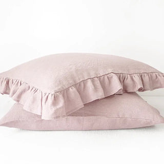 Ruffled natural linen pillowcase in pink, made from 100% flax linen, styled on a soft neutral bed – available in multiple colours and sizes from Arkaim Home.
