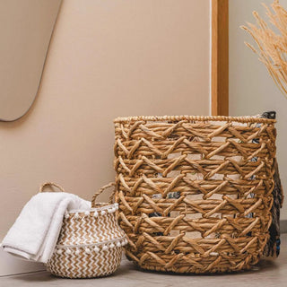 Handwoven natural and white seagrass storage basket with handles, perfect as a stylish hanging basket, pot planter, or decorative storage solution. This eco-friendly, two-tone basket adorned with charming pom poms adds a touch of natural boho touch while keeping your space organized. Shop handcrafted storage baskets at our natural homeware store.