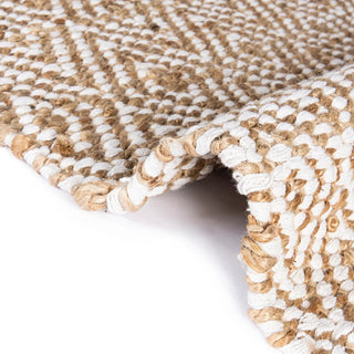 Handwoven two-tone jute rug with tassels and geometric pattern for boho, nordic, or coastal interiors.