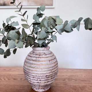 Handcrafted ribbed ceramic vase with antique white wash and urn-like silhouette displayed with eucalyptus stems. A timeless decorative piece for rustic, wabi-sabi, or minimalist interiors.