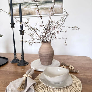 Rustic ceramic vase styled with spring blooms and branches.
