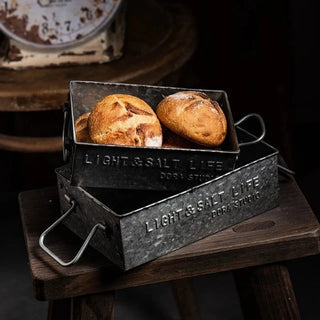 Handmade black rustic iron trays with vintage finish and side handles, ideal for serving bread or organising pantry items.